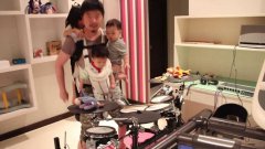 Dad performs one-handed drum cover while holding his three kids